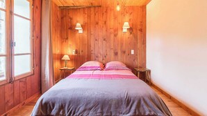 A wooden-paneled room with a bed, two bedside lamps, and a window.