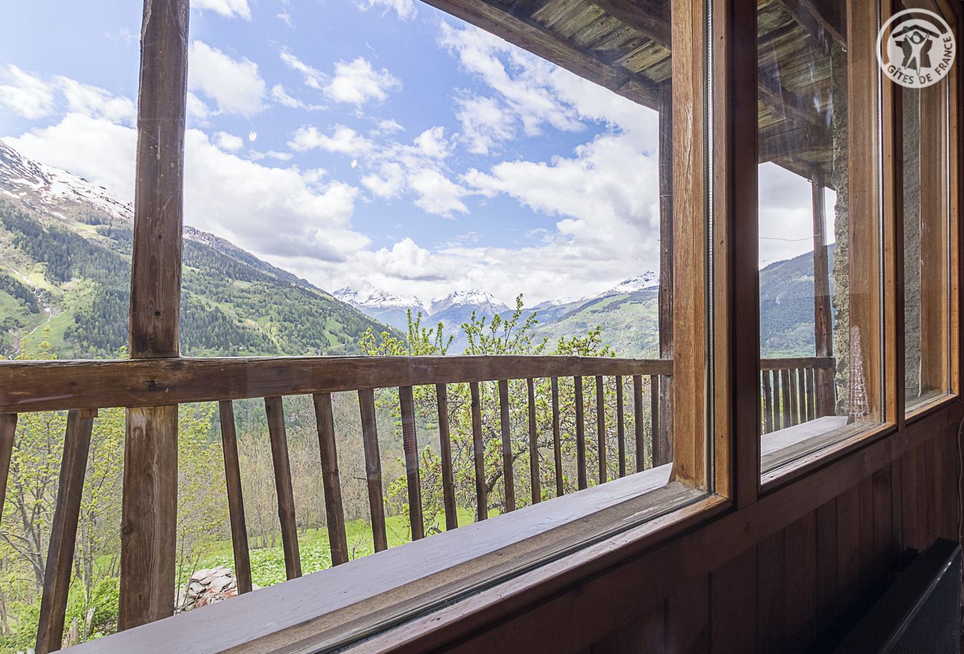 Un balcón de madera con vistas a montañas nevadas y un cielo despejado.