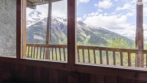 A wooden balcony with a view of snow-capped mountains and a clear sky.