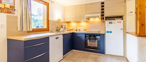 Cocina compacta con lavavajillas, horno y cocina integrada.