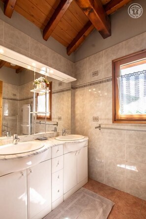 A bathroom with two sinks, a large mirror, and a window with a curtain.