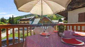 A table set outdoors with a tablecloth, chairs, and a table umbrella. - CHALET L'ALBARON - SAINT SORLIN D'ARVES (SAINT SORLIN D'ARVES)