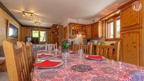A dining area with a long table set for six, wooden chairs, and a decorative tablecloth. - CHALET L'ALBARON - SAINT SORLIN D'ARVES (SAINT SORLIN D'ARVES)