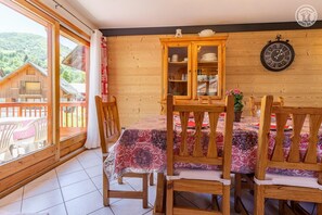 Un comedor de madera con una mesa dispuesta para cuatro personas, sillas, un aparador con vajilla y un reloj en la pared.