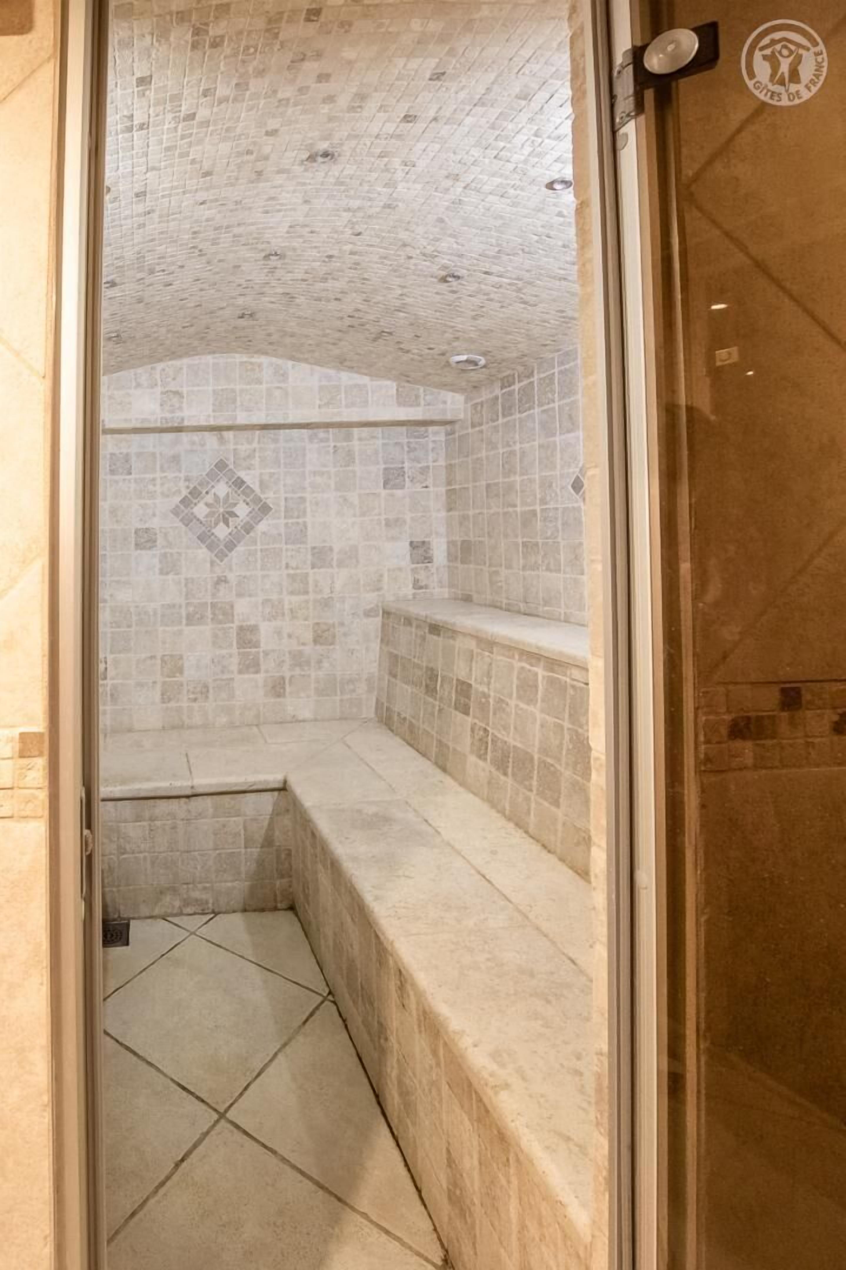 Un petit espace de douche carrelé, doté d’un banc.