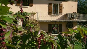 A two-story building with a balcony, a small garden area, and a window with shutters. - LA GRIVE - CLERY - Gîte (CLERY)