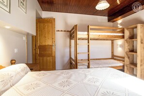 Een kamer met stapelbedden, een houten deur en een ladder.