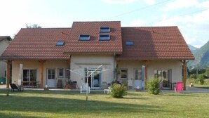 A two-story house with a red-tiled roof, a front porch, and a small garden area.