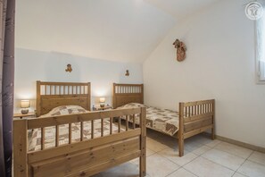 A room with two wooden beds, each with a nightstand and a lamp. The room has a sloped ceiling and a decorative wall hanging. - GITE VIGNE - MYANS - Vacation Home (MYANS)