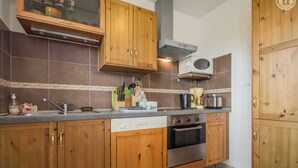 A kitchen with wooden cabinets, a stainless steel oven, a microwave, and a range hood.