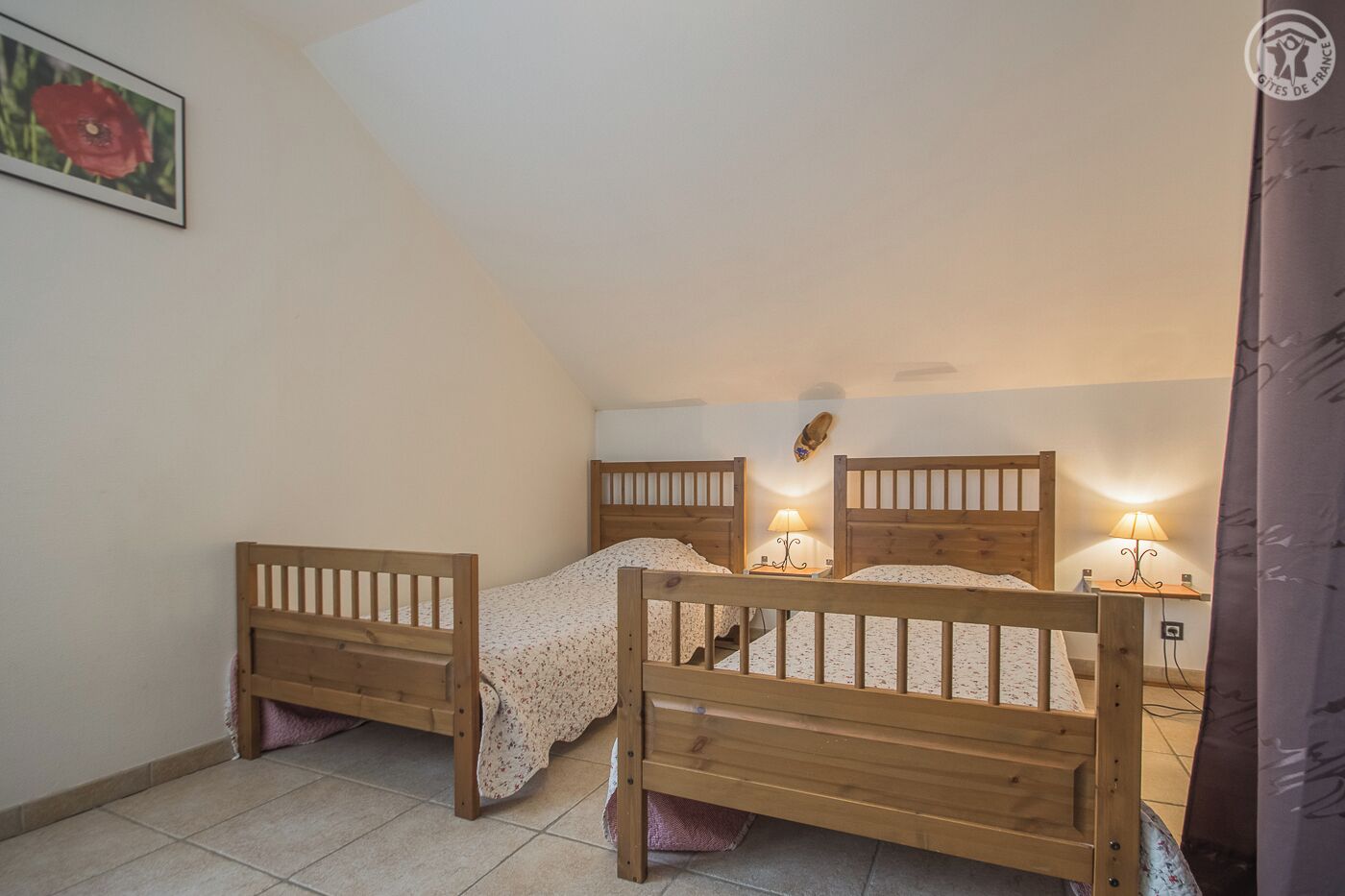 A bedroom with two wooden beds, a small table, and a lamp.