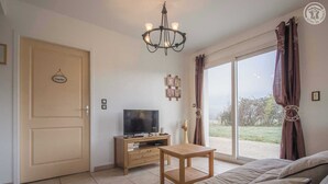 A modern living room with a TV, wooden furniture, and a large window with curtains.