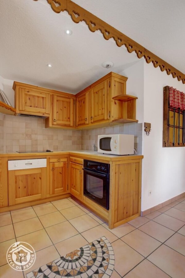 A kitchen with wooden cabinets, a microwave, and an oven.