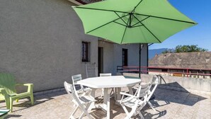 A patio with a round table and chairs, a green umbrella, and a view of the mountains. - MUSCARIS - AIX LES BAINS (AIX LES BAINS)
