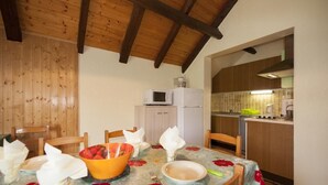 Uma área de refeições com uma mesa posta para quatro pessoas, micro-ondas e cozinha ao fundo.