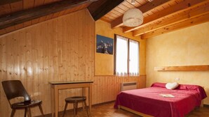 Um quarto de madeira com uma cama, uma escrivaninha e uma cadeira.