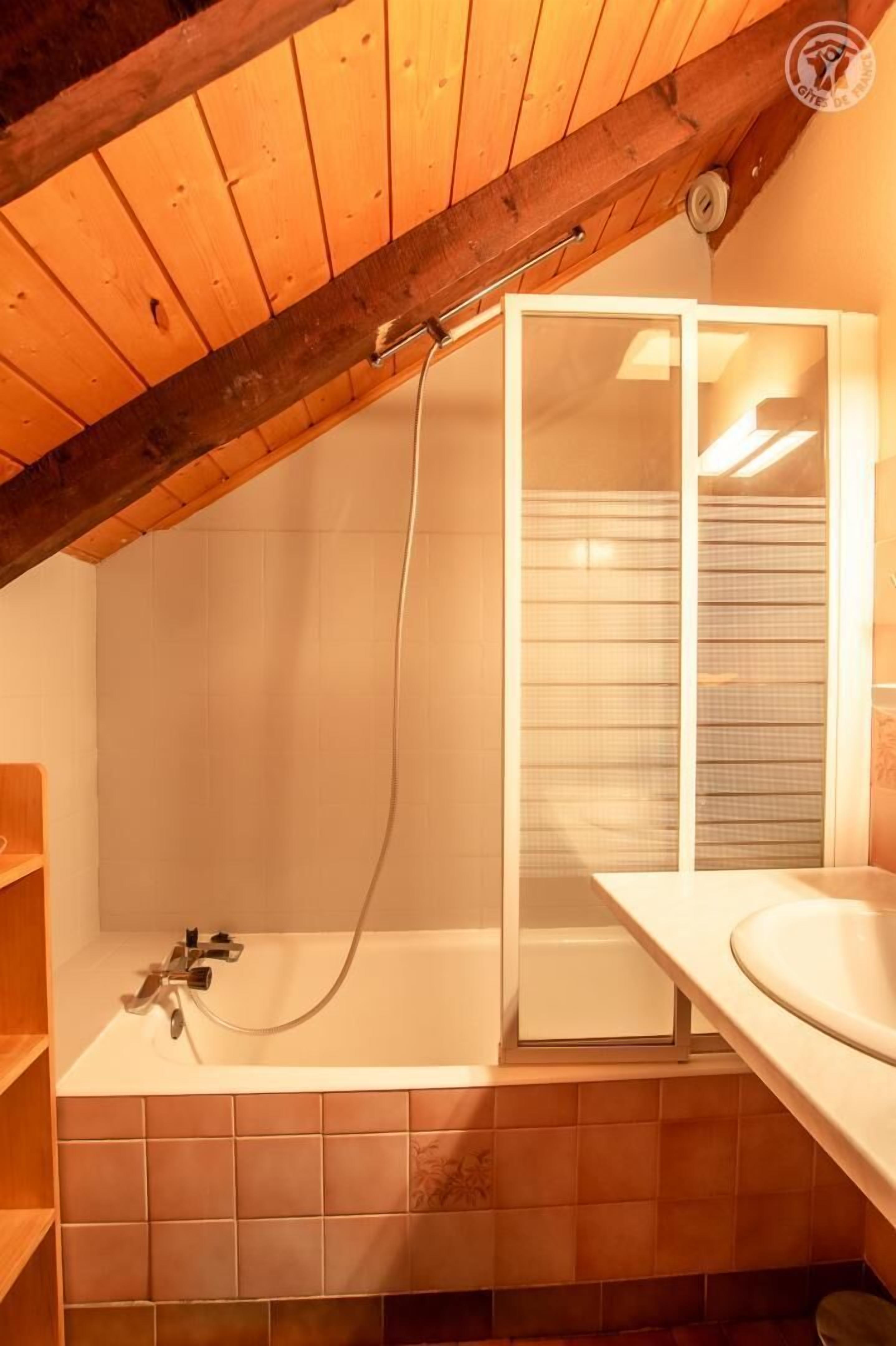 Ein Badezimmer mit Holzboden, einer Badewanne, einer Duschkabine aus Glas und einem Waschbecken.