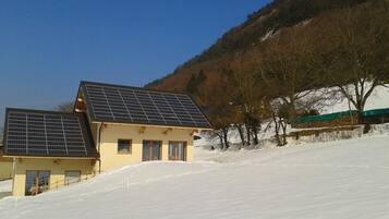 Une maison dotée de panneaux solaires sur le toit, située sur une colline enneigée.