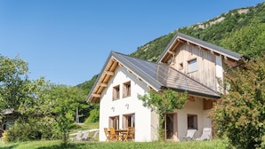 Un chalet à deux étages, doté d’un toit en pente, d’une façade en bois et d’un balcon.