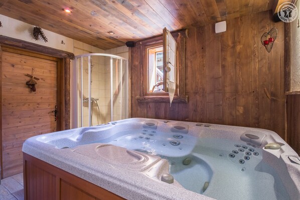 A wooden cabin with a hot tub, wooden walls, and a window.