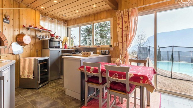 A cozy kitchen with wooden walls and a dining area with a red tablecloth.