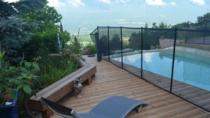 A wooden deck with a pool, a lounge chair, and a bench.