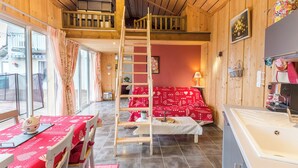 A cozy room with a bunk bed, a dining area with a table and chairs, and a kitchenette.