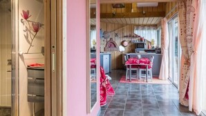 A modern kitchen with a red and white checkered tablecloth, a wooden ceiling, and a pink wall.