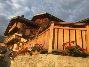 Una cabaña de madera tradicional con un balcón y macetas con flores.
