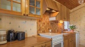 A kitchen with wooden cabinets, a tiled backsplash, a stove, a sink, and a toaster. - LE BARBIER - AUSSOIS (AUSSOIS)