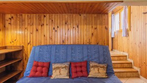 A room with a wooden sloped ceiling, a bed with blue bedding and red pillows, and a staircase leading to a window with curtains. - LE BARBIER - AUSSOIS (AUSSOIS)