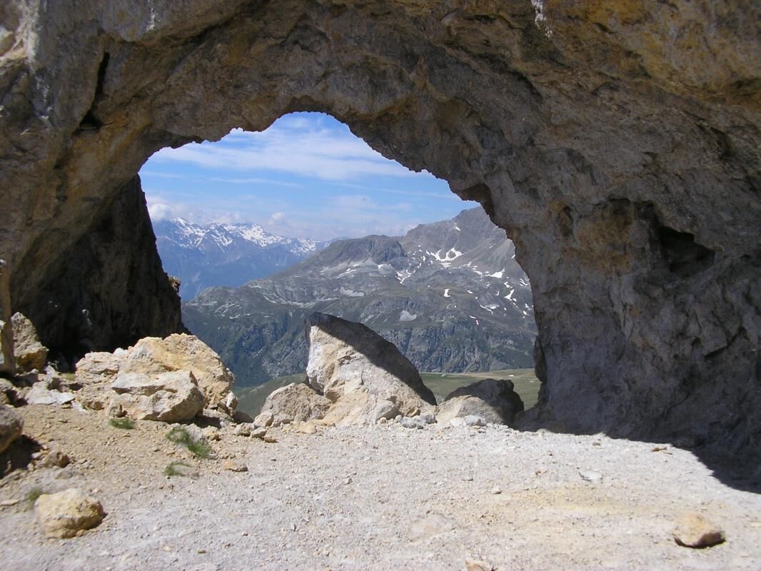 L'entrée d'une grotte rocheuse, d'où l'on peut admirer des montagnes aux sommets enneigés.