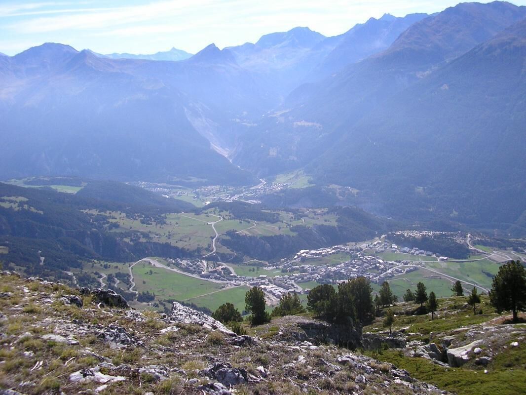 Un paysage montagneux avec une vallée et une petite ville.