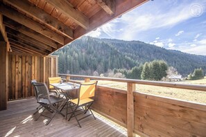 Enjoy a serene mountain view from this deck with a table and chairs.