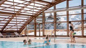 An indoor swimming pool with clear views of snowy mountains through large windows. - BIO CORTI LODGE - CHAMPAGNY EN VANOISE (CHAMPAGNY EN VANOISE)