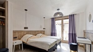 A bedroom with a wooden headboard, two beds, a desk, and a chair. - BIO CORTI LODGE - CHAMPAGNY EN VANOISE (CHAMPAGNY EN VANOISE)