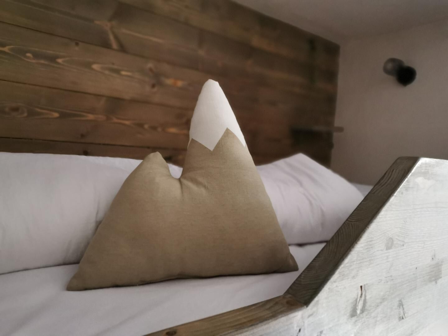A bed with a wooden headboard, a white pillow, and a brown pillow.