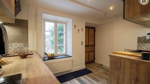 A kitchen with a window, wooden cabinets, a radiator, and a black countertop.