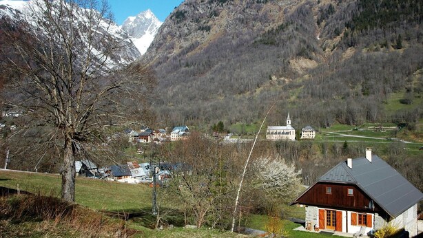 Un pueblo de montaña con casas tradicionales, una iglesia y un lago.