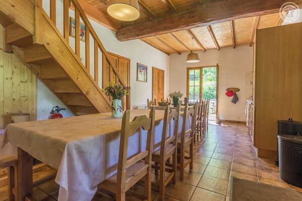 A dining area with a long wooden table, chairs, and a staircase.