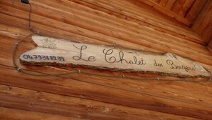 Un letrero de madera con un número y texto en la pared de una cabaña.