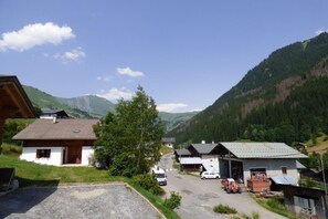 A rural village with houses, a gravel road, and a mountain backdrop.