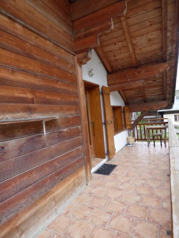 A wooden cabin with a covered porch, wooden walls, and a tiled floor.