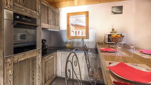 A kitchen with wooden cabinets, a built-in oven, a sink, and a dining area with a table set for two.