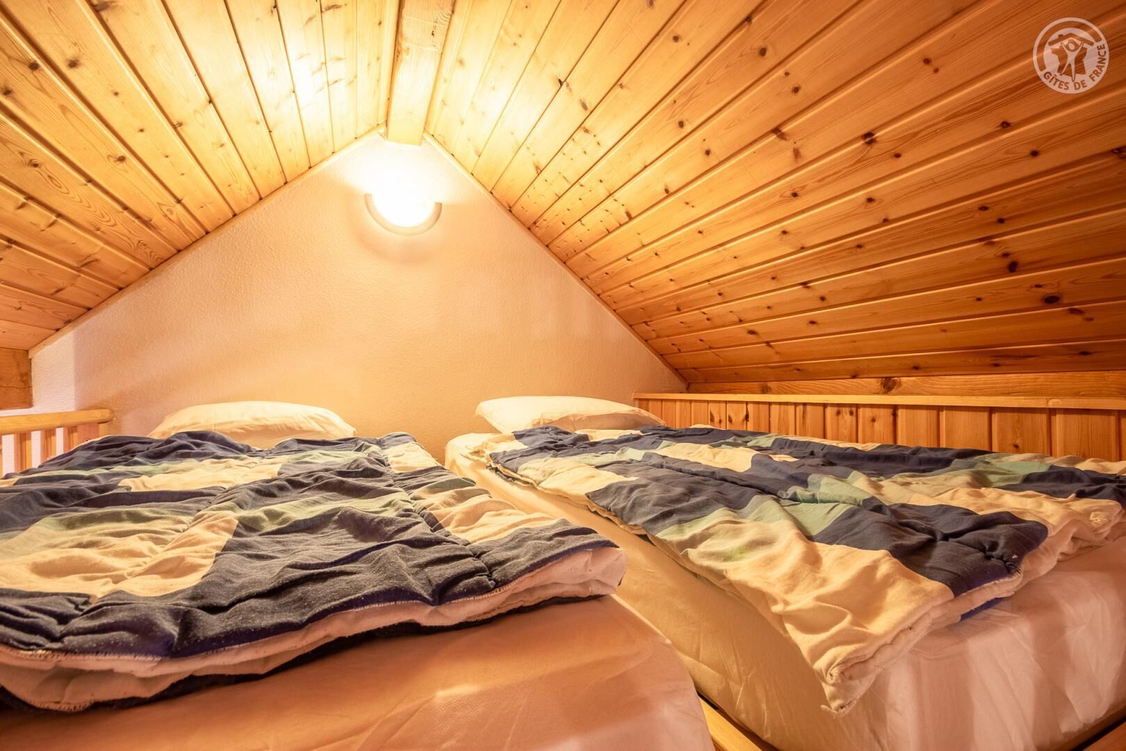 Een gezellig slaapkamer op zolder met twee bedden, houten plafond en dakraam.