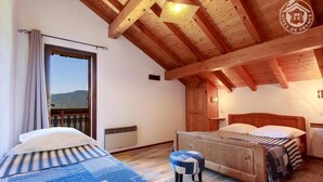 Un dormitorio con estructura de madera, una cama, un banco y vistas al exterior.