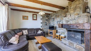 Una sala de estar acogedora con chimenea de piedra, un sofá de cuero y un televisor.