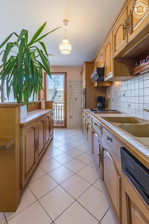 Uma cozinha com armários de madeira, uma ilha grande, um lustre e um vaso de planta.