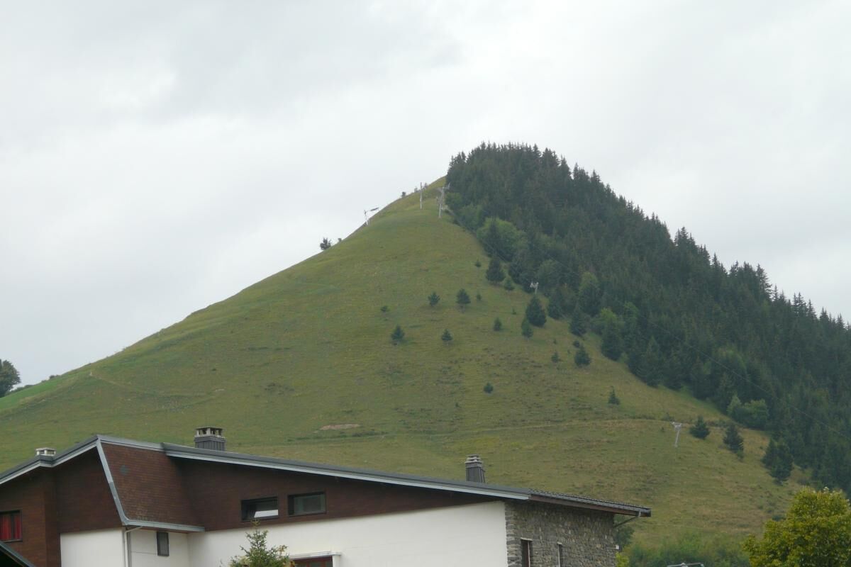 A house with a sloped roof, a chimney, and a small window.