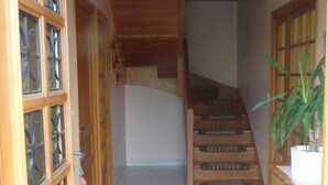 Un pasillo con una escalera, armarios de madera y una planta en maceta.